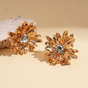 Vintage gold daisy earrings with crystals on beige stone background for elegant style
