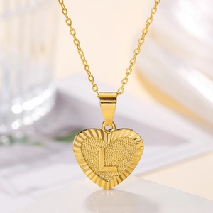 Detailed close-up of golden heart pendant with embossed letter L and textured sunburst edges
