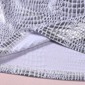 Macro view of silver snakeskin texture fabric with mesh lining and stitched hem detailing