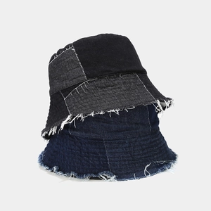 Detail of distressed denim bucket hat with frayed edges and patchwork design in two colors