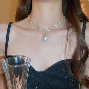 Macro shot of a luxury pear-shaped water drop crystal pendant necklace on a model's collarbone