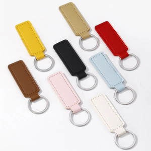 Flat lay of eight colorful faux leather keychains with metal rings on white background