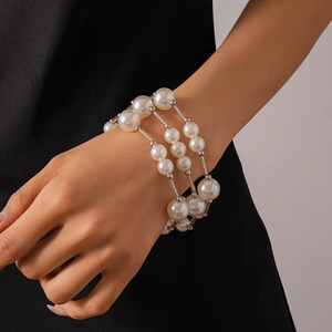 Gros plan sur un bracelet triple rang en perles et éléments argentés porté au poignet