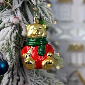 Christmas bear ornament set in red, green and gold hanging on a snowy Xmas tree