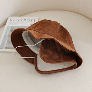 Détail d'un chapeau bob en velours côtelé marron avec doublure sherpa blanche et lanière