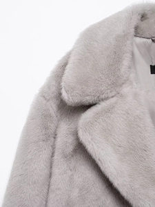 Detail view of the soft faux fur texture and collar of a gray long winter coat for women