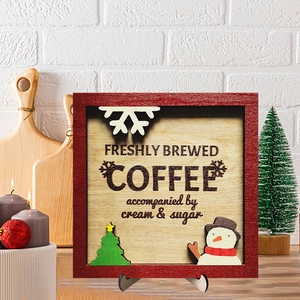 Christmas wooden coffee sign with snowman and tree motifs on a warm festive kitchen table
