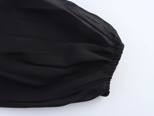Détail du poignet élastique froncé sur une manche de robe en mousseline noire légère
