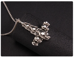 Detailed view of silver skull stacked pendant with delicate box chain on black texture