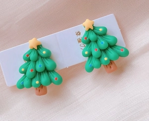 Macro detail of cute Christmas tree clip-on earrings with colorful resin star ornaments