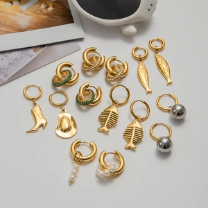 Parure de boucles d'oreilles en acier doré avec perles et breloques créatives sur blanc