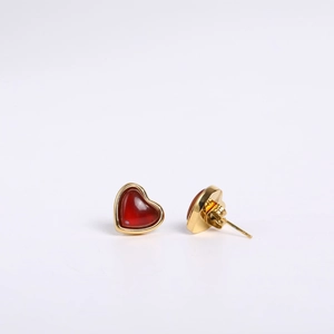 Detailed close-up of heart-shaped gold studs with red gemstone inlay and secure metal backs