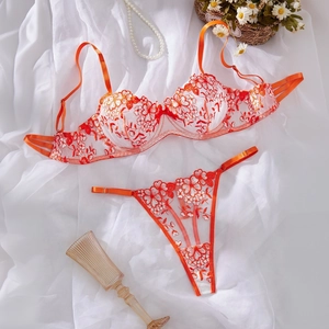 Detail of floral embroidery on orange-red lace bra and thong with pearl accents