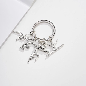 Close-up of silver metal gymnastics keychain with silhouette charms and heart pendant