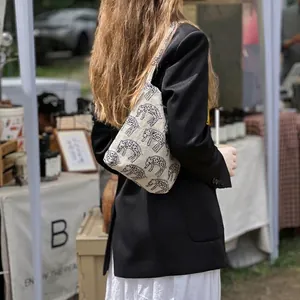 Artistic canvas shoulder bag with blue elephant embroidery pattern in outdoor market