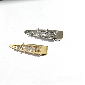 Detailed close-up of two sparkling star-shaped rhinestone hair clips in gold and silver