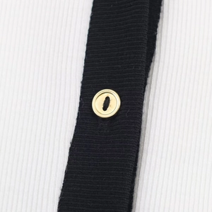 Detail of ribbed knit fabric with black and white contrast and a gold button