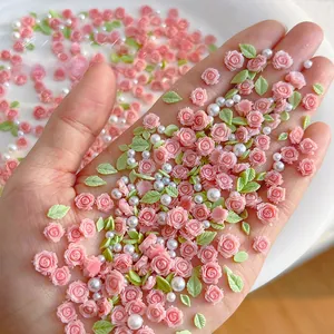 Macro detail of pink resin roses, green leaves and white pearls for 3D nail art design