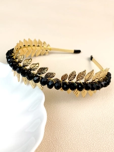Detailed view of handmade leaf headband with black crystal beads on a white shell dish