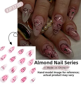 Detail of pink almond press-on nails with rose gold heart and bow-knot designs