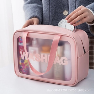 Detail of large pink PU and PVC travel washbag with handle being filled with cosmetics