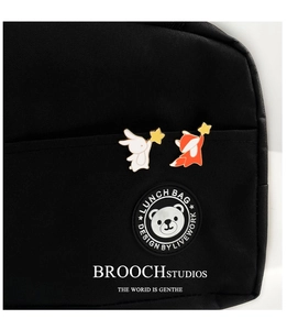 Detail of cute enamel rabbit and fox pins with stars on a black canvas lunch bag
