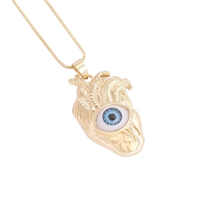 Détail macro du pendentif cœur en or 18 carats avec œil bleu réaliste sur chaîne box