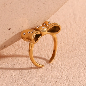 Detail of 18K gold plated bow ring featuring micro-pave crystals on textured stone