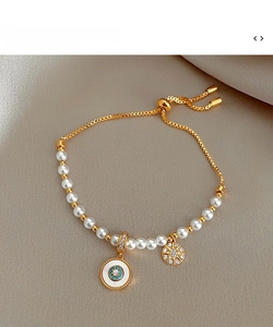 Détail du bracelet perles dorées avec charms œil et étoile sur fond en tissu