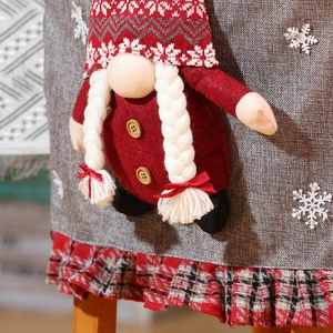 Detail of Christmas chair cover featuring a gnome with long braids and red plaid trim