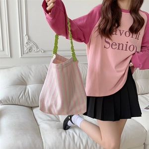 Detailed shot of striped canvas tote bag with green ruched handle and pink stripes
