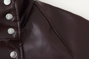 Detailed macro view of dark brown PU jacket featuring four metallic silver snap buttons