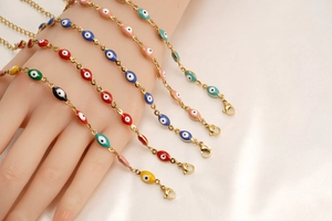 Detalle de pulseras coloridas Evil Eye apiladas en la muñeca con cadenas de metal dorado