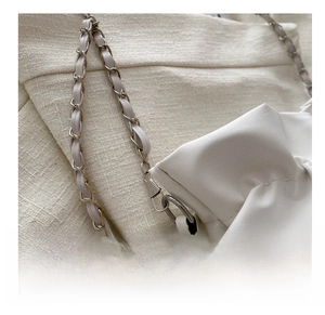 Detail of silver hardware hook and leather chain strap on white pleated bucket bag