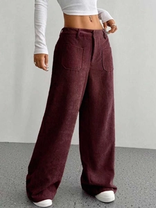 Dettaglio dei pantaloni a gamba larga in velluto a coste rosso vino a vita alta e texture