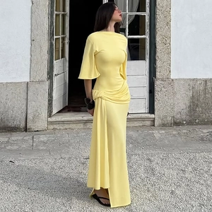Detail of the yellow backless maxi dress featuring waist pleats and draped side ribbons
