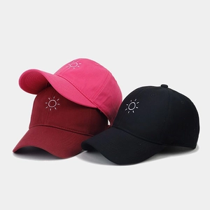 Close-up of baseball caps with sun embroidery in rose red, maroon, and black cotton canvas