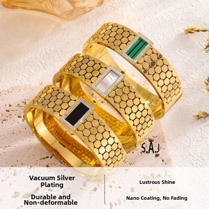Detail of gold titanium bangles with honeycomb texture and colorful stone inserts