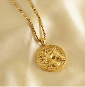 Macro shot of 3D horse head relief pendant on a gold box chain with silk background