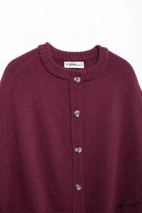 Detailed macro view of burgundy knit cardigan with amber-patterned buttons and neck label