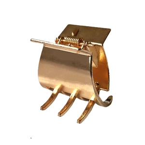 Minimalist gold metal hair claw clip with a three-prong design on white background