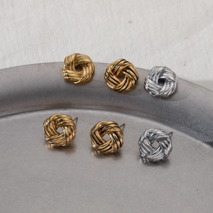 Three pairs of twisted knot earrings in gold and silver finish on a display tray