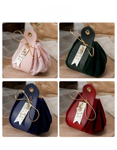 Detailed view of luxury velvet wedding favor bags with gold handles and pearl tags