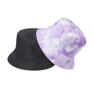 Detail of reversible bucket hats in solid black and purple marble tie-dye canvas fabric