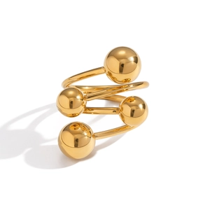 Makro-Detail eines goldenen Spiralrings mit polierten Metallkugeln und glänzendem Finish