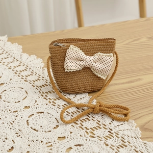 Detail showing handwoven straw crossbody bag with large polka dot lace bow decoration
