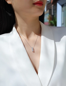 Macro shot of silver necklace featuring a vertical three-stone pendant on model