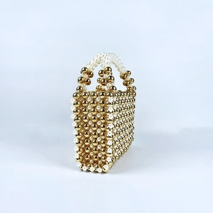 Detail of handmade beaded handbag showing gold beads and white pearls weaving texture