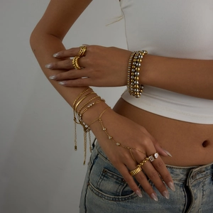 Detail view of 18K gold-plated beaded bracelets and matching ring on a fashion model
