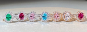 Reihe von Halo-Ringen mit Ovalschliff in Smaragd, Rubin und Aquamarin auf Textur